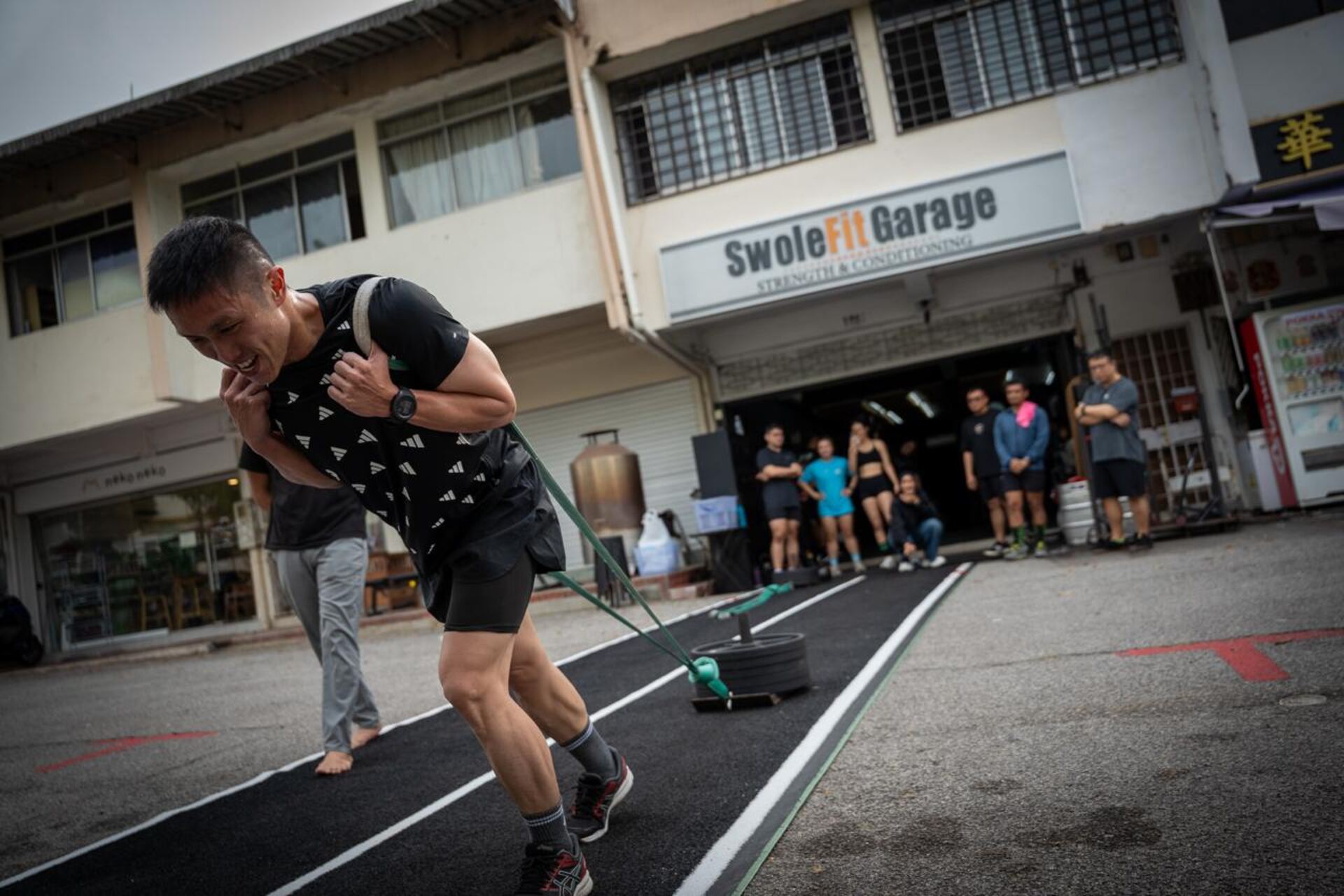 A member training with a sled outside the SwoleFit Garage storefront on Jalan Malu-Malu